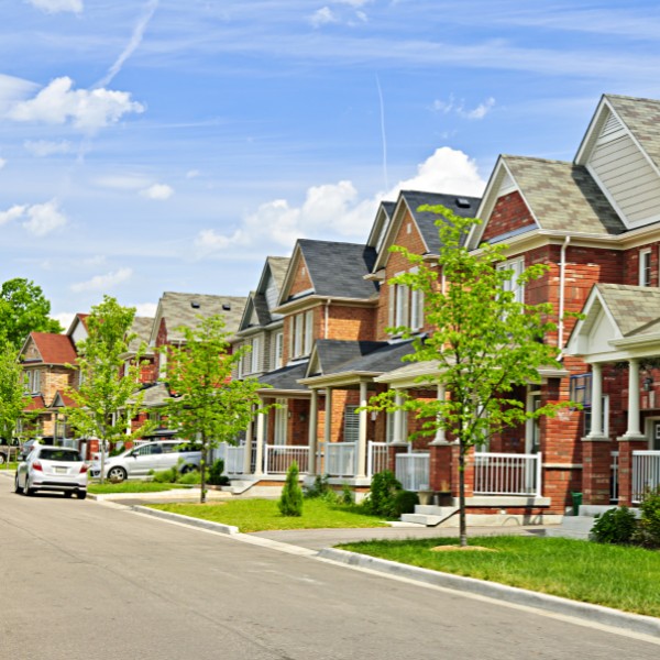 Website-Heatherwilde-section-houses-trees-summer Heatherwilde neighborhood with houses lining the street, green grass, and small trees under a blue sky with some clouds.
