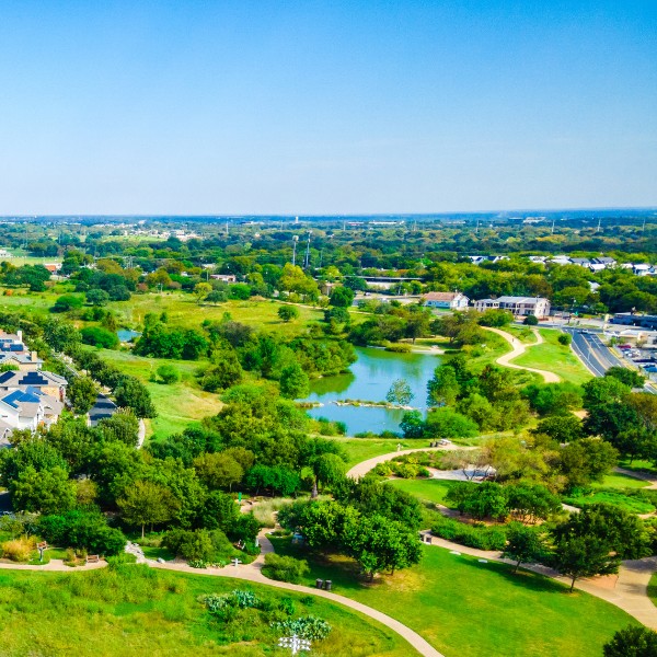 Website-Hyde-section-mueller-lake Mueller Lake near Hyde Park, surrounded by walking paths, green grass, mature trees, and nearby neighborhoods, on a clear, sunny day.