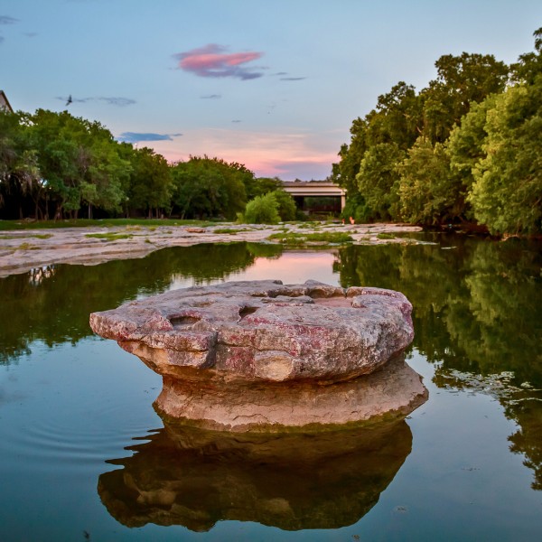 Website-Lafrontera-section-round-rock-stream Small pond with a large rock in the center and a bridge in the background.