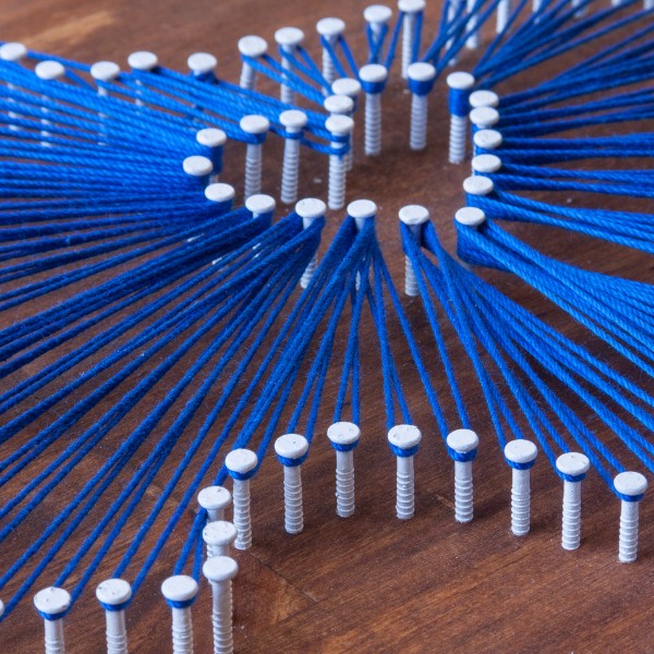 Website-Liberty-section-string-art-nails String art on a wooden board featuring the outline of Texas, with blue string forming a heart shape in the center using nails.