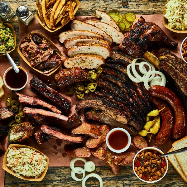 Website-Northaustin-section-beef-chicken-bbq Table filled with Southern BBQ staples in North Austin, including beef, chicken, pork, coleslaw, fries, potatoes, and baked beans.