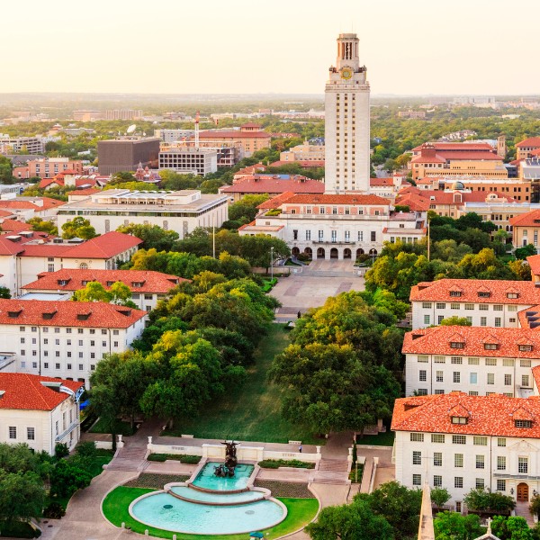 Website-Northwest-section-austin-uiversity-buildings Overhead view of the University of Texas at Austin campus with white buildings, rusty orange roofs, a central fountain, and surrounding green trees and grass.