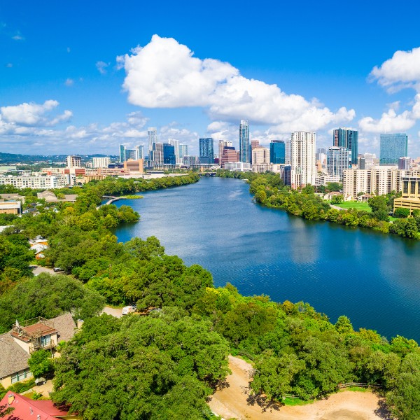 Website-consultation-section-river-parks-trees Bright blue water in the Colorado river flowing between green trees and tall building that make up the skyline in Austin, TX.